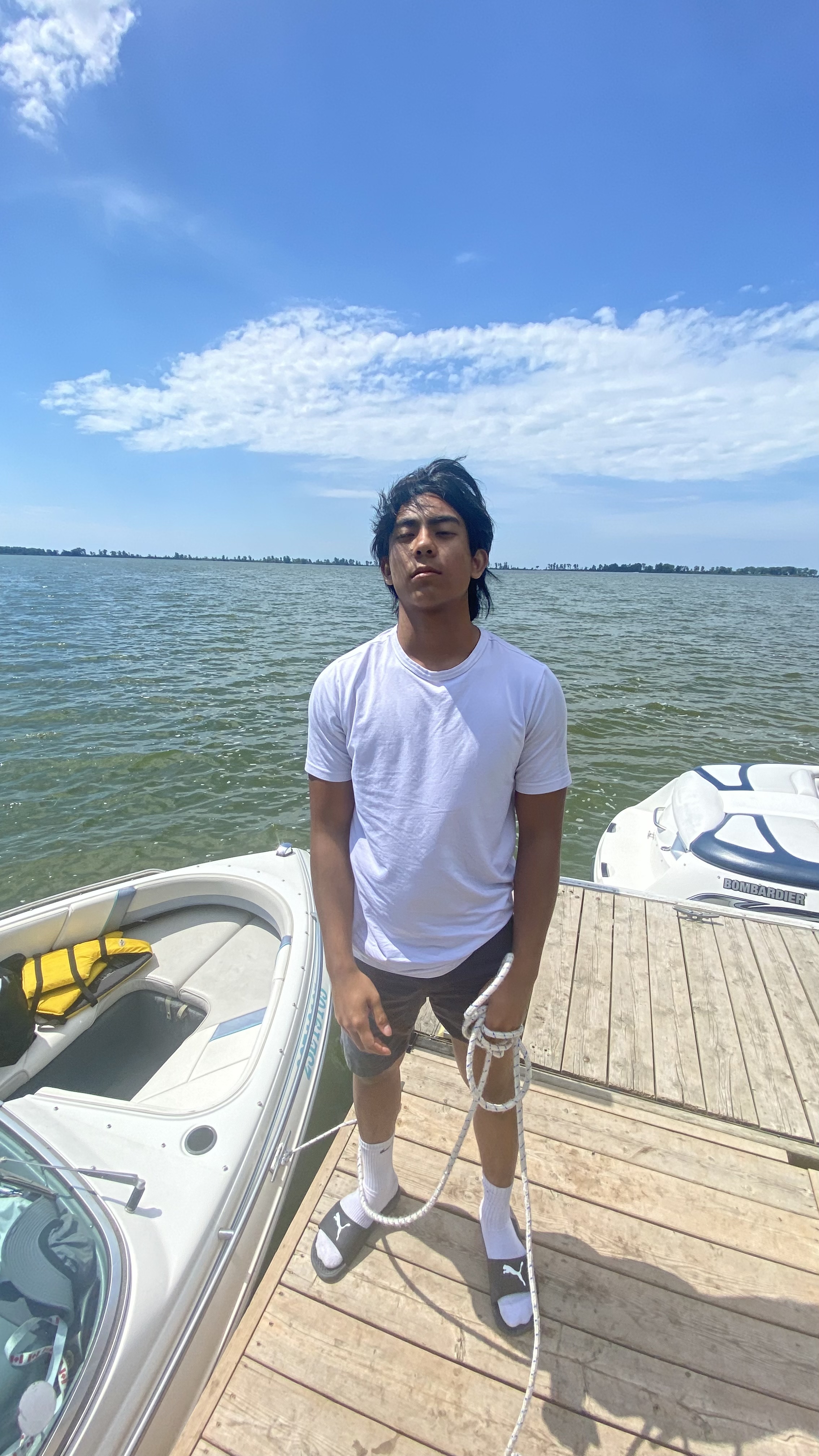 Daniel in a white shirt standing on a dock by the lake.