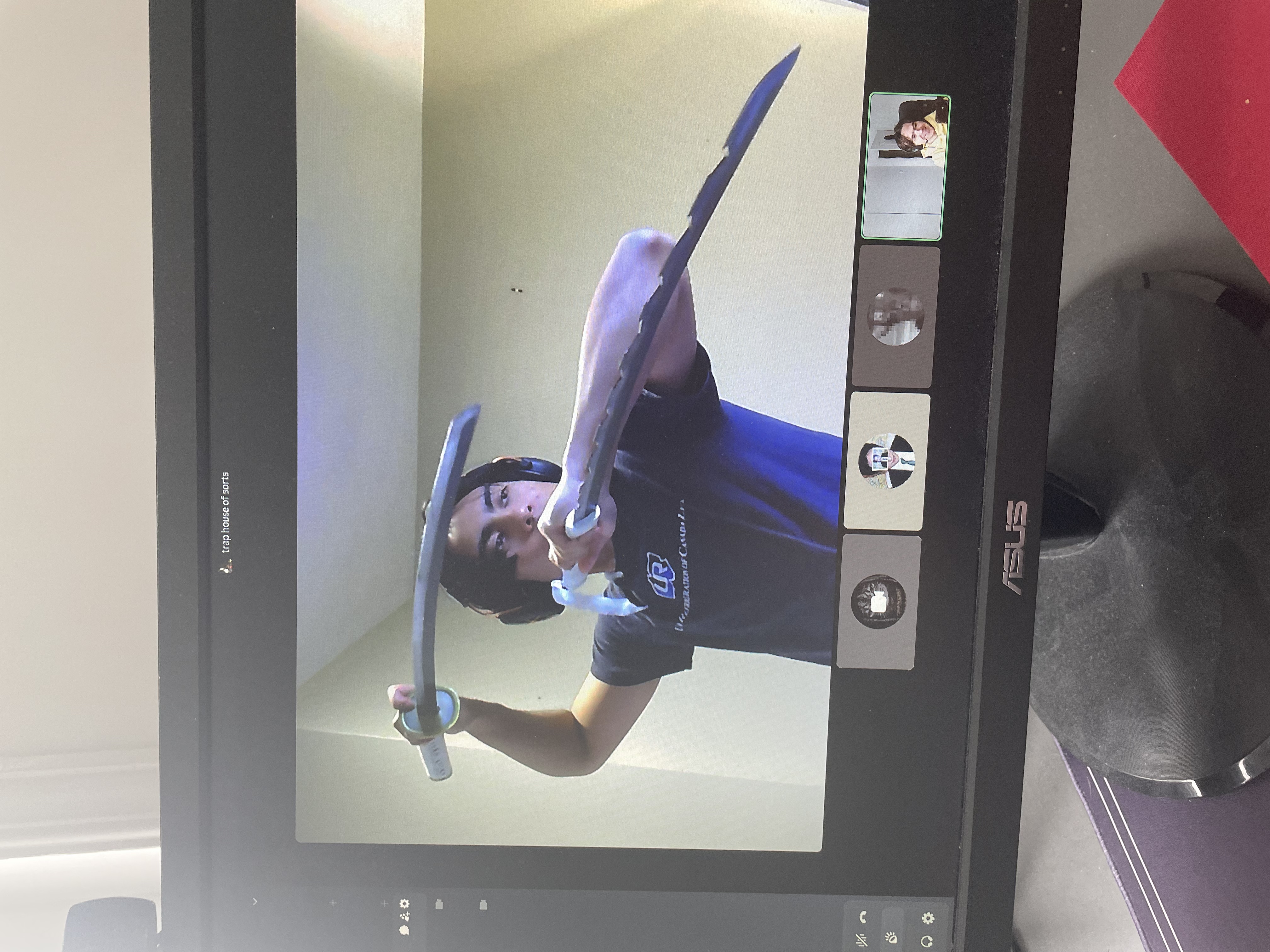 Daniel posing with prop swords on a video call.