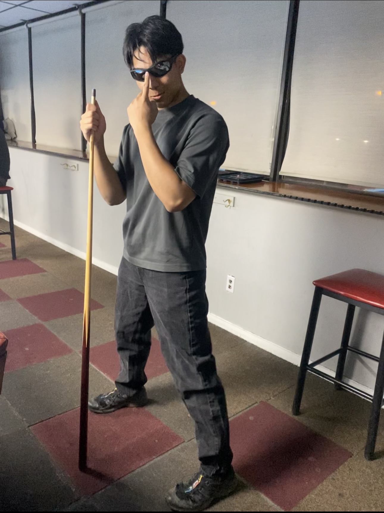 Daniel holding a pool cue while posing in sunglasses.